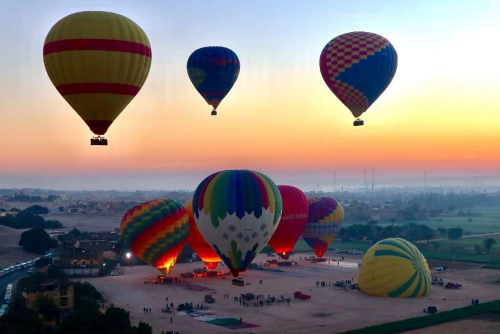 Hot air balloons ascending and descending at dawn with an orange and yellow sky